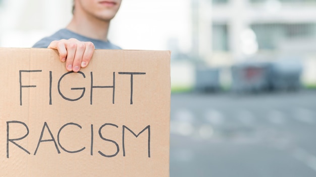 Free photo man holding fight racism quote on cardboard copy space