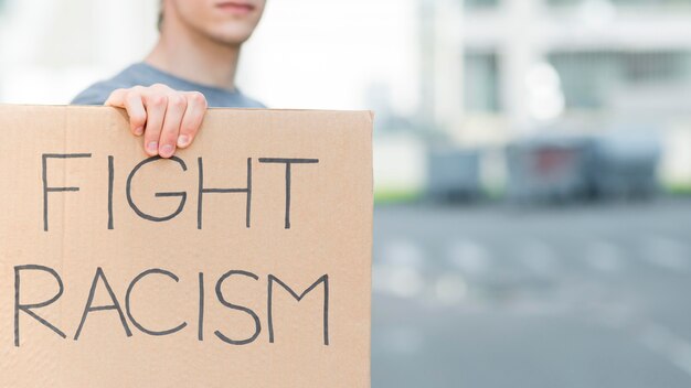 Man holding fight racism quote on cardboard copy space