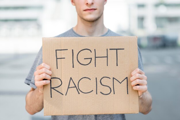 Man holding fight racism quote on cardboard