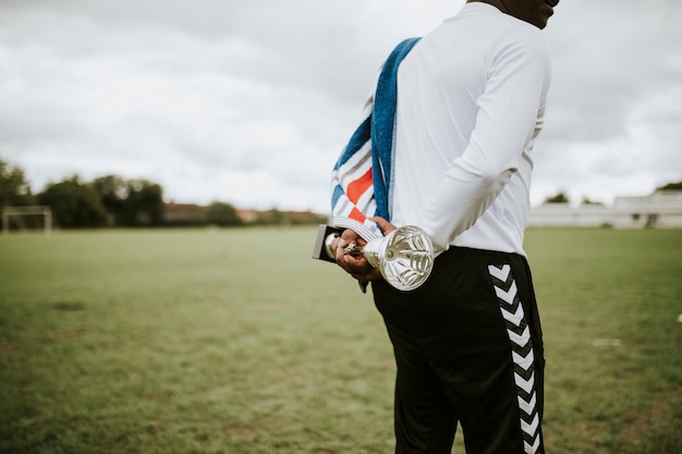 Free photo man holding a flag and a trophy