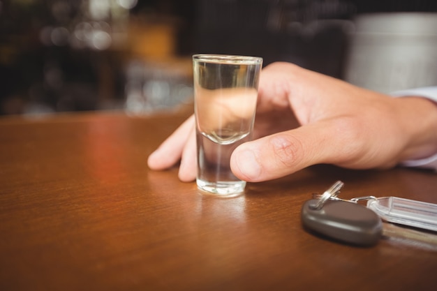 Man holding glass of tequila shot in bar counter