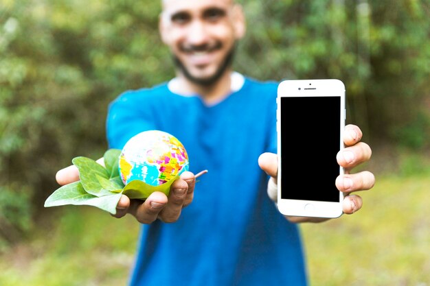 Man holding globe with leaf and smartphone