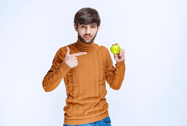 Man holding a green apple and promoting it to the customers.