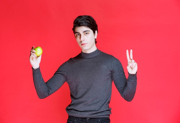 Man holding a green mandarin and enjoying it