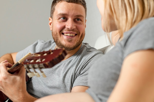 Мужчина держит гитару и смотрит на свою жену