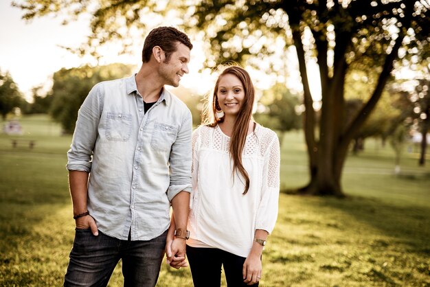 Man holding hand of woman standing near tree