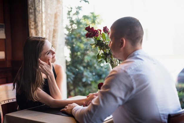 Free photo man holding hand of young woman and sitting at table