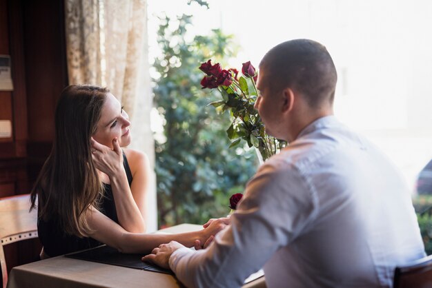 Man holding hand of young woman and sitting at table