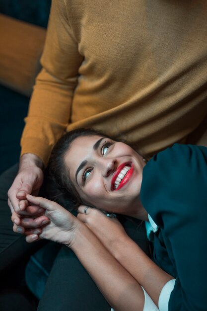 Man holding hands with cheerful woman lying on legs