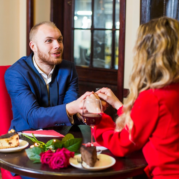 Free photo man holding hands of woman at table in restaurant