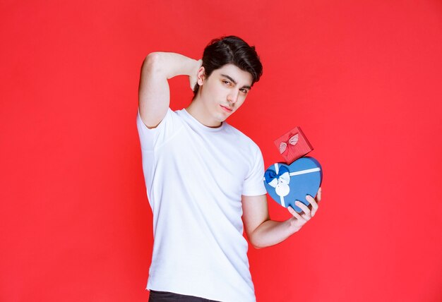 Man holding heart shape gift boxes and flirting. 