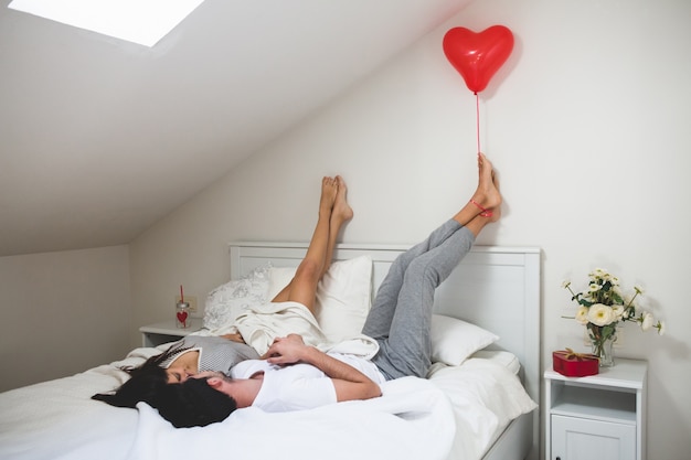 Man holding a heart shaped balloon with his feet
