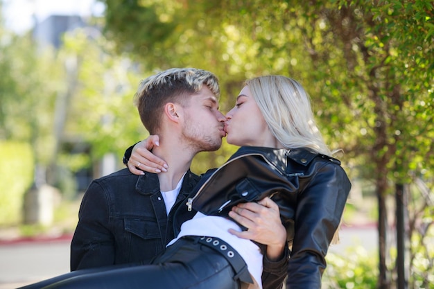Мужчина держит девушку на коленях и целует Фото высокого качества