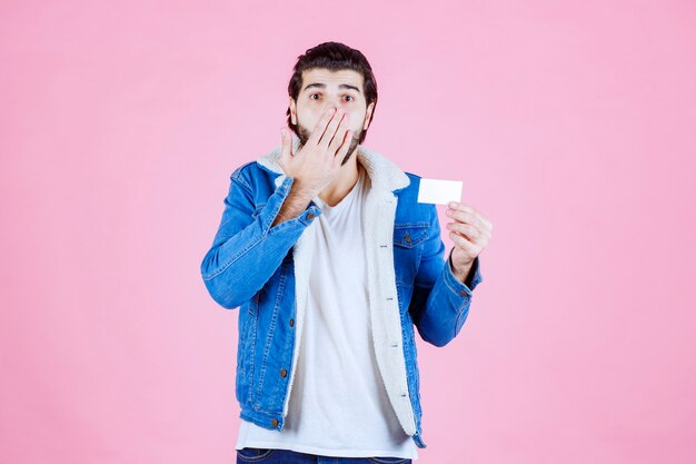 Man holding his business card and looks surprized