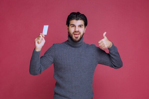 Man holding his business card and makes positive hand sign.