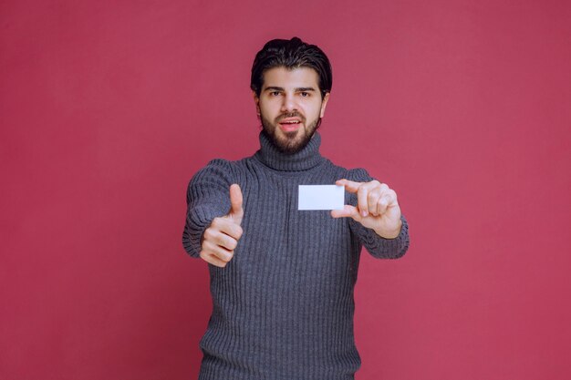 Man holding his business card and makes positive hand sign.