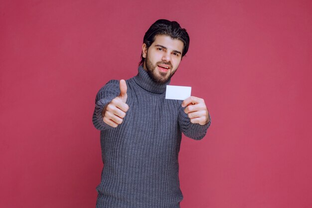 Man holding his business card and makes positive hand sign.
