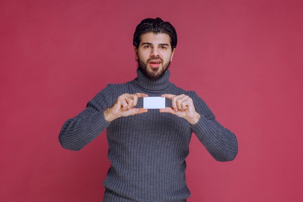 Free photo man holding his business card, presenting or recieving it.