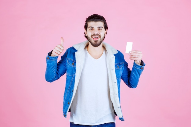Man holding his business card and showing thumb up