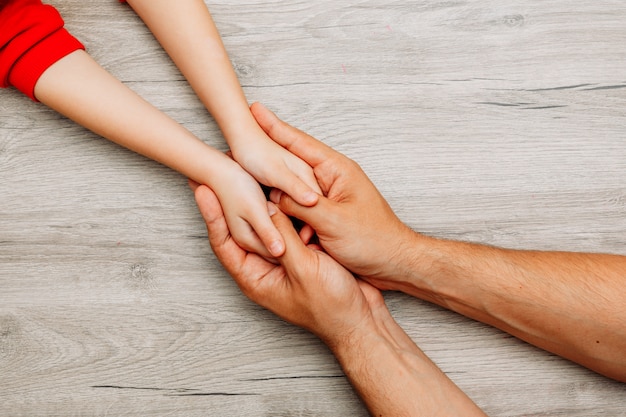 Man holding his daughter's hands on a light wooden