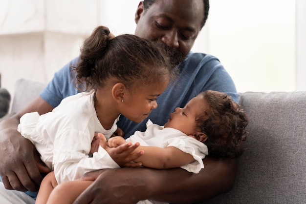 Free photo man holding his daughters in his arms