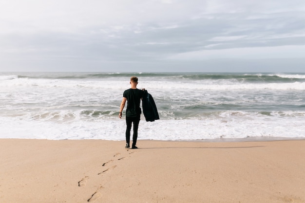 Man holding his jacket on beach