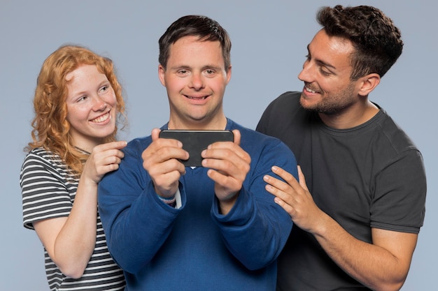 Бесплатное фото Мужчина держит свой телефон для фотографирования со своими друзьями
