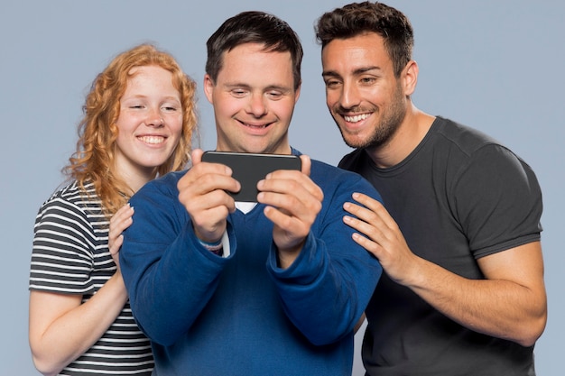 Free photo man holding his phone for taking a selfie with his friends