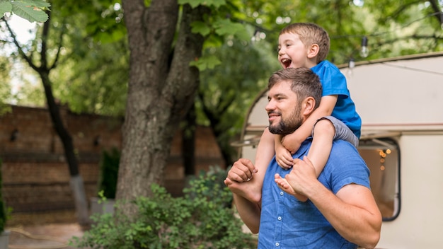 Man holding his son on his shoulders with copy space