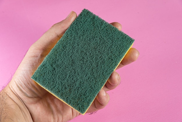 Free photo man holding kitchen sponge on the pink background