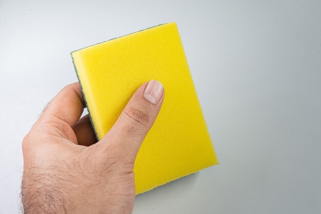 Man holding kitchen sponge on the white background