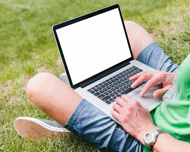 Мужчина держит ноутбук в парке