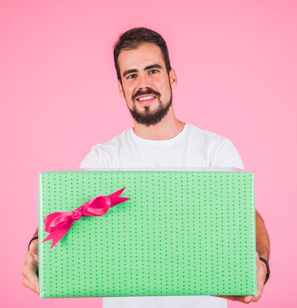 Man holding large gift box with bow against pink background