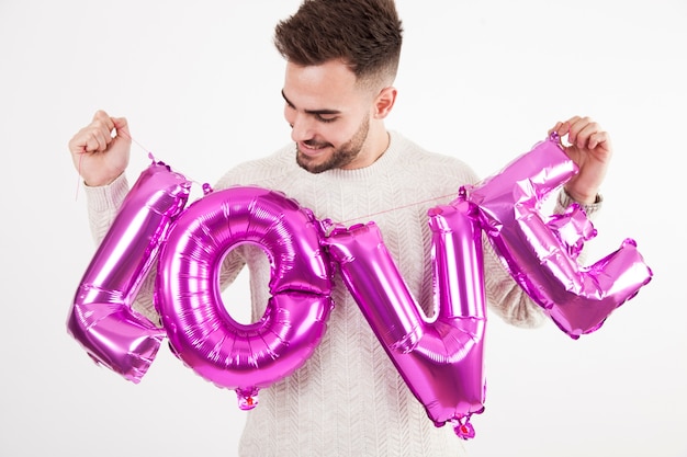 Man holding love writing from balloons