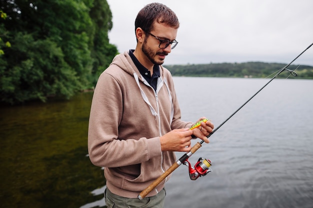 Man holding lure and fishing rod near the lake