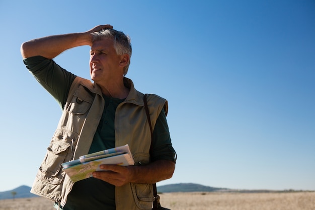 Free photo man holding map on landscape