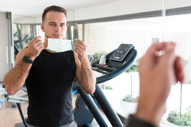 Free photo man holding medical mask at the gym