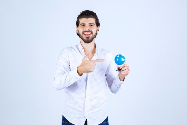 Man holding a mini globe and looking at it