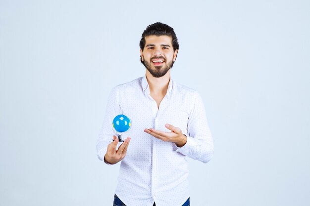 Man holding a mini globe and looking at it