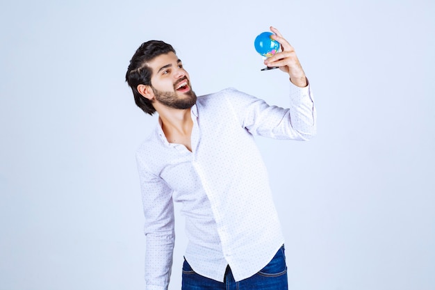 Man holding a mini globe and looking at it