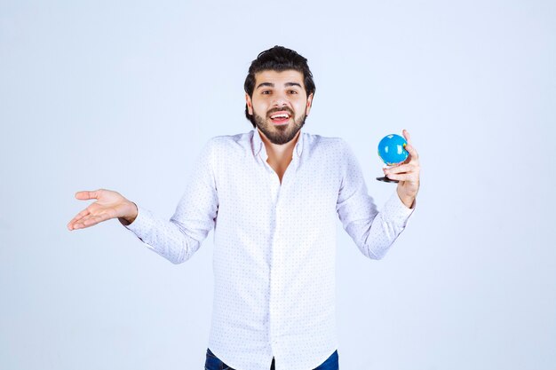 Man holding a mini globe and looks confused