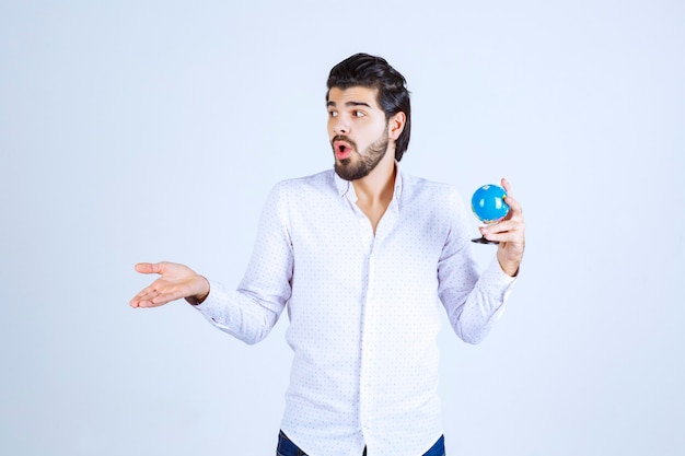 Man holding a mini globe and looks confused