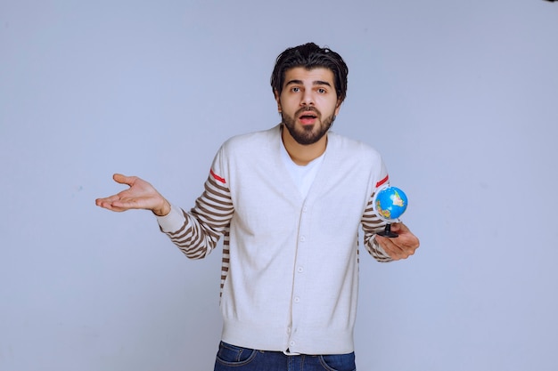 Man holding a mini globe and looks like he has no knowledge on geography.