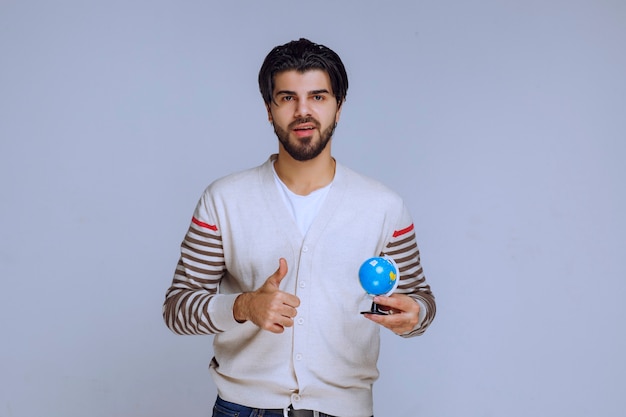 Man holding a mini globe and looks like he studied all the locations and map.