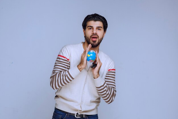 Man holding a mini globe and looks like he studied all the locations and map.