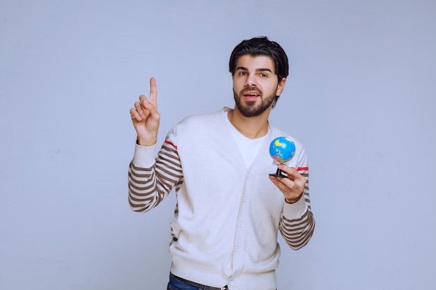 Uomo che tiene un mini globo e rivolto verso l'alto.