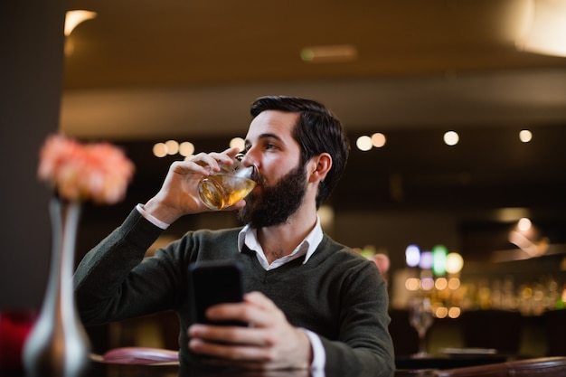 Мужчина держит мобильный телефон и выпить