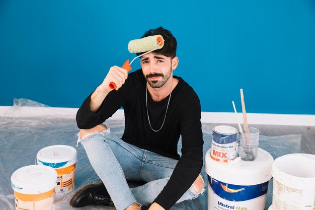 Man holding paint roll at head