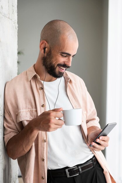 Man holding phone and cup