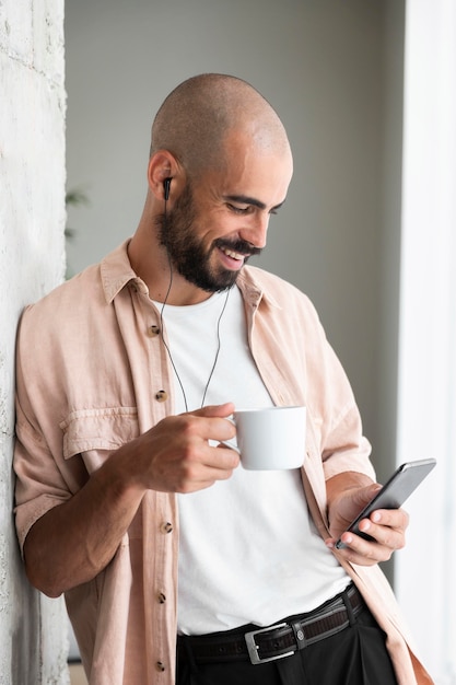 Man holding phone and cup